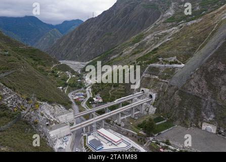 (231128) -- MAOXIAN, Nov. 28, 2023 (Xinhua) -- This aerial photo taken on Nov. 13, 2023 shows a train for commissioning and testing running through Liutongzhai Tunnel in southwest China's Sichuan Province. A 238-km section of the Sichuan-Qinghai railway in western China became operational on Tuesday after 12 years of construction.   The railway crosses the rugged, earthquake-prone plateau region in northwest Sichuan, and takes a detour to avoid disturbing the Giant Panda National Park.      The Sichuan-Qinghai railway will eventually stretch northwestward to Xining, the capital city of Qinghai Stock Photo