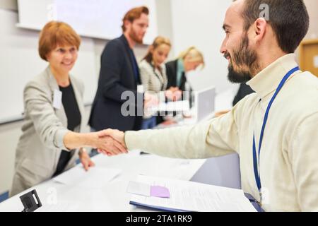 Female orator handshaking with audience at stage during business event in auditorium Stock Photo