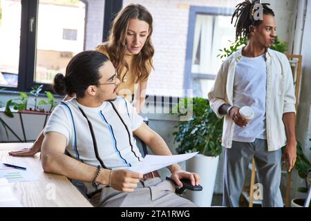 team lead with documents sitting near multiethnic colleagues working on startup in office, planning Stock Photo