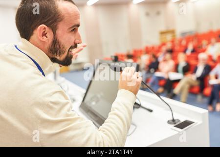 Male orator speaking through microphone at podium in business conference at auditorium Stock Photo