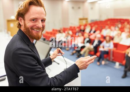 Portrait of happy male speaker at business conference discussing with audience through microphone Stock Photo