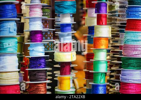 Different coloured borders on rolls, colourful border made of fabric, rolled up ribbons for sewing work at a market stall, close-up, Valencia, Spain Stock Photo
