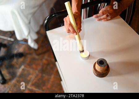 Therapist prepare burning mugwort or moxa herb to apply to 50s adult fit caucasian female patient to facilitate healing and blood flow, in Stock Photo