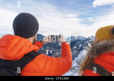 Mountaineers take photo of snowy landscape in the mountains with their dog in winter Stock Photo