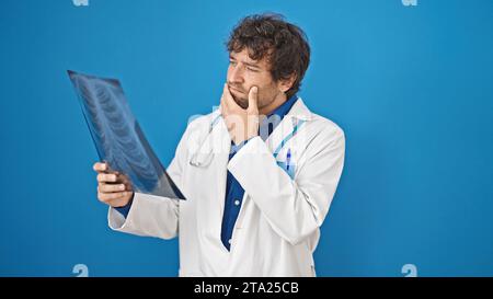 Young hispanic man doctor looking xray over isolated blue background Stock Photo