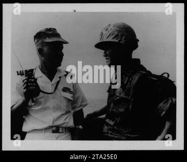 ARVN soldiers, including Vietnamese marines, engage in a military operation during the Vietnam War in 1962. The soldiers are seen cautiously advancing through dense vegetation, ready for combat. The image captures the tense and uncertain environment faced by American allies during the conflict. Stock Photo