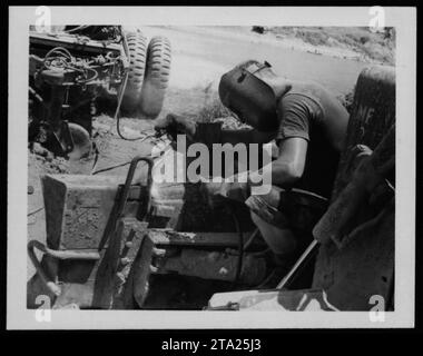 A group of military personnel are seen engaging in maintenance activities on May 23, 1970 in ME (presumably Maine). The image shows soldiers working together, potentially repairing equipment or conducting inspections, as part of their duties during the Vietnam War. Stock Photo