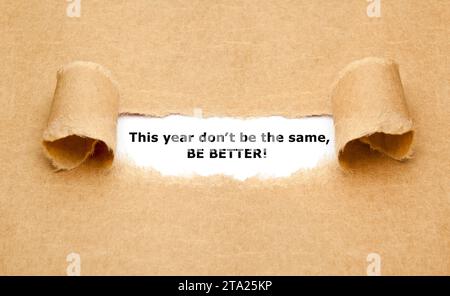 Inspirational quote This Year Do Not Be The Same, Be Better appearing behind torn brown paper. Motivational New Year goal concept. Stock Photo