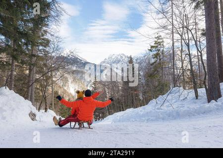 Joyful couple slides on a snow sled through a beautiful snowy forest Stock Photo