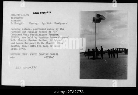 Marines and Popular Forces of the 'T' Combined Unit Pacification Program (CUPP) participate in the Morning Colors ceremony in Vietnam on August 9, 1970. Lance Corporals T.H. Fionie and G.M. Alaniz, assisted by local Popular Forces, hold the American flag during the ceremony. This photograph was taken by Sergeant O.L. Snodgrass and is part of the US Defense Department collection. Stock Photo