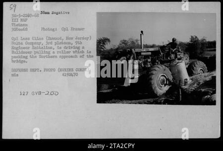 Delta Company, 3rd Platoon, 9th Engineer Battalion, is seen in this photograph taken on December 30, 1968, during the Vietnam War. The image shows a bulldozer being driven by Cpl Kramor and Cpl Lass Cline from Rowood, New Jersey. They are using the bulldozer to pull a roller, which is used to pack the Northern approach of the bridge. This photograph was taken by the Marine Corps and is labeled as 4192470 mis 127 GVB-200. Stock Photo