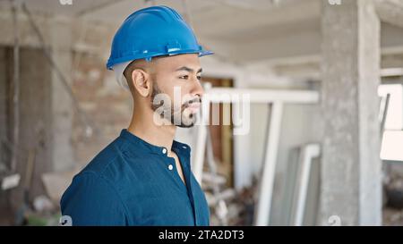 Young hispanic man architect wearing hardhat with serious face at construction site Stock Photo