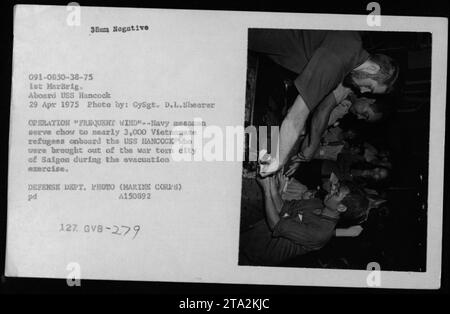 Caption: During Operation Frequent Wind in 1975, Navy messmen serve meals to approximately 3,000 Vietnamese refugees aboard the USS Hancock. These refugees were evacuated from the war-ravaged city of Saigon as part of the exercise. This photograph, taken by GySgt. D.L. Shearer, documents the efforts of the American military during the Vietnam War. Stock Photo