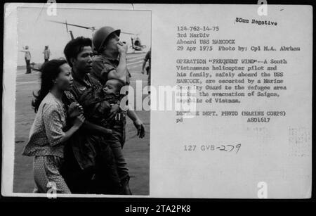 'South Vietnamese helicopter pilot and his family being escorted to the refugee area by a Marine Security Guard aboard USS HANCOCK during the evacuation of Saigon, Republic of Vietnam in Operation Frequent Wind - April 29, 1975. Photo by Cpl M.A. Abrhan, Defense Dept. Photo (Marine Corps).' Stock Photo