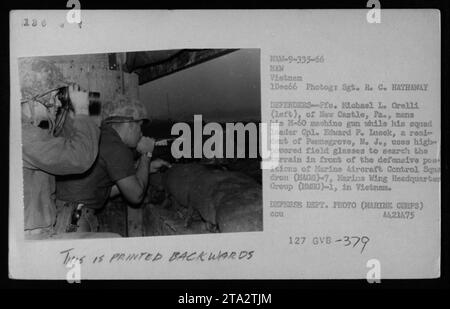 'Pfc. Michael L. Orelli operates an M-60 machine gun while Cpl. Edward P. Lueck scans the terrain using high-powered binoculars. They are both members of Marine Aircraft Control Squadron (HAGS)-7, Marine Wing Headquarters Group (MHG)-1, in Vietnam, providing defense to their positions. Photograph taken on December 1, 1966 by Sgt. R. C. Hathaway.' Stock Photo