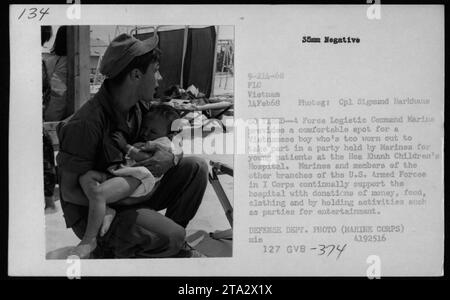 Marine provides a resting spot for a tired Vietnamese boy during a party organized by the US Armed Forces for young patients at Hoa Khanh Children's Hospital in February 1968. The Marines regularly support the hospital with donations and activities to provide entertainment for the patients. Stock Photo