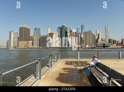 New York, USA - May 25, 2018: A man in Brooklyn Bridge Park with financial district in lower Manhattan at the background. Stock Photo