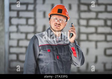 A professional worker at a construction site using a smartphone is always in touch with the customer or foreman Stock Photo