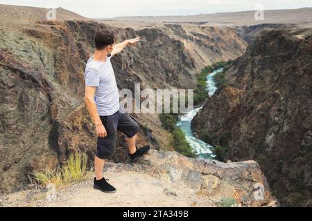 Man tourist stand and look on upper part of the Charyn River, which flows through the Charyn Canyon in Kazakhstan in the Almaty region Stock Photo