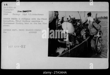 A rifleman from the First Battalion, Third Marines conducts a search on a Vietnamese fishing boat on the Cua Viet river in 1968. This image, taken by LCpl P.L. Schackmann, captures a routine activity of American military personnel during the Vietnam War. Stock Photo