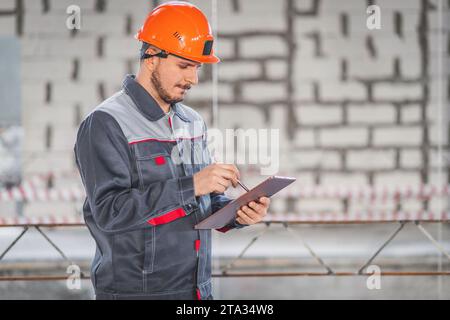 A builder looks at a project on a digital tablet and checks the plans of a house being built on a construction site, copy space Stock Photo