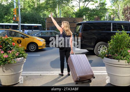 New York, USA - May 24, 2018: Woman catches a taxi at the street in New York. Stock Photo