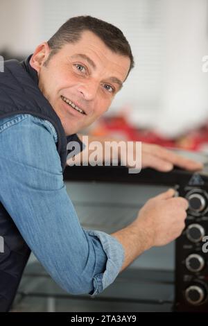 mature man repairing electric oven Stock Photo