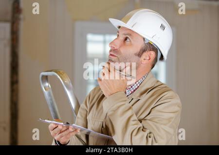 mature builder writing something on site plans Stock Photo