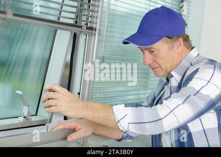 young repairman fixing window frame in room Stock Photo