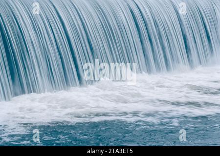 Blue water in motion over waterfall in to white foam bubbles of the river Stock Photo