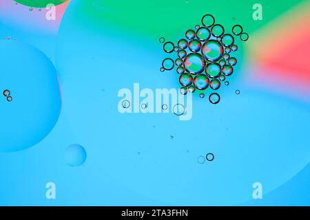 Macro photo with circles oil droplets water surface. Abstract blue, green and red background with oil bubbles Stock Photo