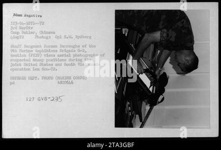 Staff Sergeant Norman Burroughs of the 9th Marine Amphibious Brigade's G-2 section (PIIU) is seen viewing aerial photographs of suspected enemy positions during the joint United States and South Vietnamese operation Lom Son-72. The photograph was taken on September 4, 1972, in Camp Butler, Okinawa, by Corporal R.W. Rydberg. Stock Photo