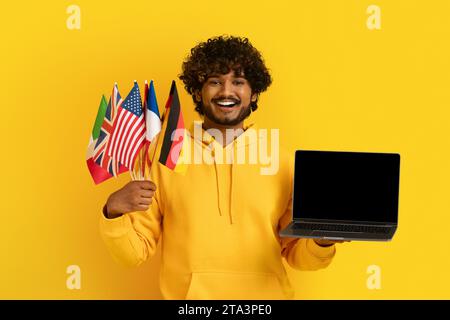 Indian man holding laptop with black screen and diverse flags Stock Photo