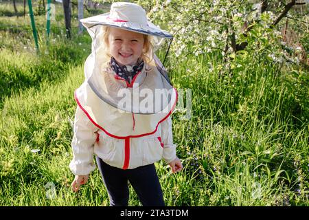 Portrait of a little girl in a beekeeper costume. Children learn how to care for bees. Stock Photo