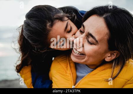 Mother and daughter having tender moment outdoor in winter day. Latin family and love concept Stock Photo