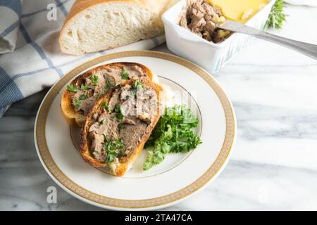 Homemade chicken liver pate on toasted white bread and served on a plate  garnished with parsley Stock Photo