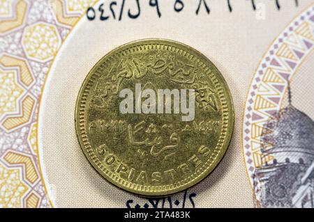 Reverse side date and value of Egyptian 50 piasters coin on Egyptian banknote, with obverse side commemorative coin features eagle head, 90 years of E Stock Photo