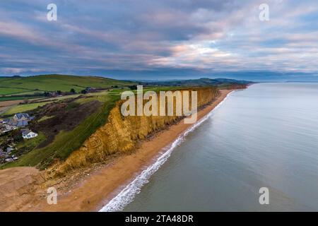 West Bay, Dorset, UK.  28th November 2023.  UK Weather.  The clouds are tinged with pink at sunset above the cliffs at West Bay in Dorset during sunset at the end of a cold and cloudy day.  Picture Credit: Graham Hunt/Alamy Live News Stock Photo