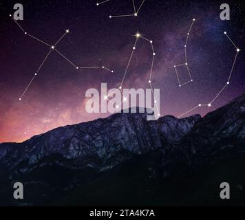 Different constellations in starry sky over mountains at night Stock Photo