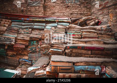 Vintage books in disarray in dimly lit, cozy room with warm sunlight streaming through window Stock Photo