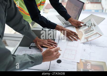 Architect and foreman discussing details on house renovation, checking blueprints and photos Stock Photo