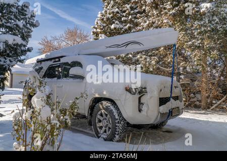 Fort Collins, CO, USA - November 25, 2023: Toyota 4runner SUV with a rowing shell, LiteRace 1x by Liteboat on roof racks covered by snow in a driveway Stock Photo