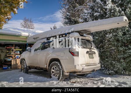 Fort Collins, CO, USA - November 25, 2023: Toyota 4runner SUV with a rowing shell, LiteRace 1x by Liteboat on roof racks covered by snow in a driveway Stock Photo