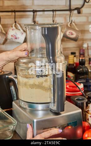 Professional chef using a modern kitchen appliance to whip cream. The skilled chef is seen in action, creating a delightful dessert in a contemporary Stock Photo