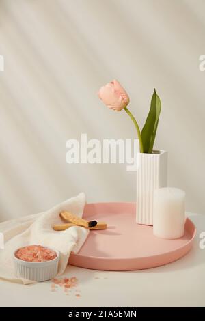 A pot with tulip flower displayed on tray with a candle and palo santo wood smoke. Ceramic bowl of pink himalayan salt on white towel. Blank space for Stock Photo
