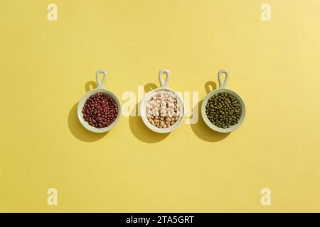 Three ceramic bowls containing red beans, soybeans and green beans arranged in a line. Beans are a strong, plant-based source of protein, fiber, iron, Stock Photo