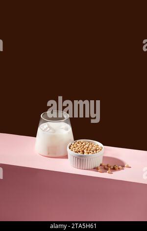 Minimal scene of a cup of fresh milk decorated with a lot of soybeans inside a white bowl. Nuts are a great source of several nutrients, including vit Stock Photo