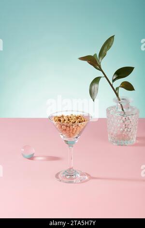 A lot of soybeans are contained inside a cocktail glass, decorated with a pot of green leaves. Soy milk contains plenty of antioxidants Stock Photo