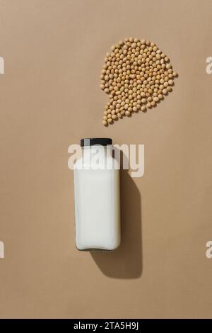 Minimal scene of an unlabeled glass bottle filled with milk displayed with a handful of soybeans. Mockup of skin care cosmetic extracted from Soybean Stock Photo