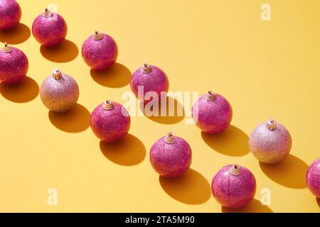 Baubles with eye-catching colors are arranged in two straight rows on a yellow background. This is a cute decoration that is often hung on the tree ev Stock Photo